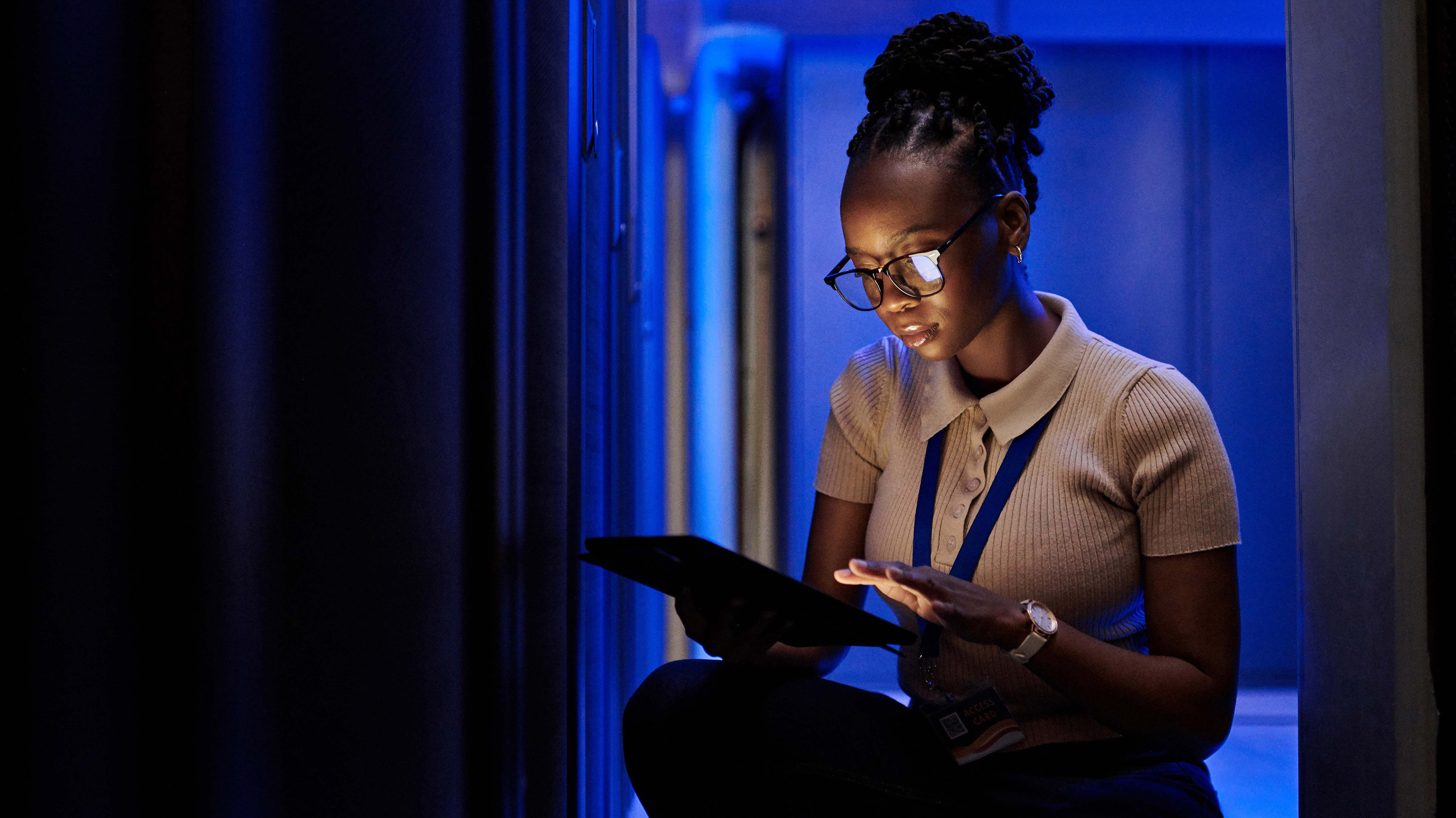 An IT professional is using a tablet to monitor and manage the server racks.